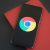 Close-up of a smartphone with Chrome browser logo on screen placed on a red notebook.